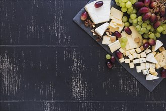 Variety cheese blocks with grapes black textured backdrop