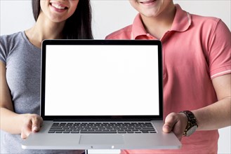 Smiling couple holding laptop showing empty white screen