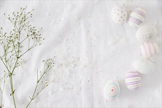 Row easter eggs with patterns near plant twig feathers textile