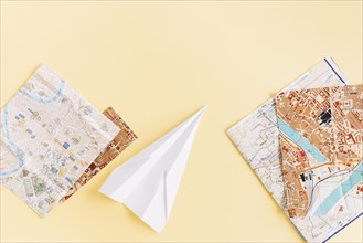 Variety maps with white paper airplane beige background