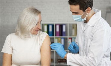 Medium shot doctor administering vaccine