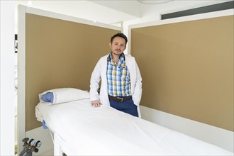 Latino doctor posing next to a table in his beauty center