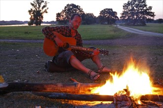 Man at a campfire playing guitar