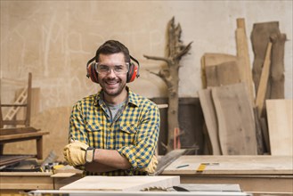 Portrait smiling carpenter wearing safety glasses ear defender workshop