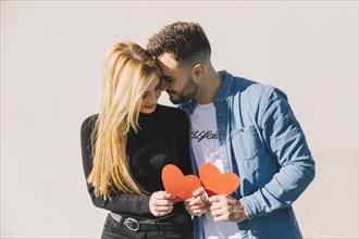 Enamored couple holding paper hearts