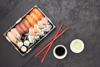 Vivid asian fish rolls tray chopsticks with soya sauce wasabi back concrete floor