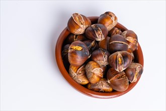 Roasted chestnuts in an earthenware casserole isolated on a white background