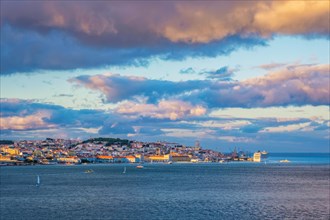 View of Lisbon over Tagus river from Almada with yachts tourist boats and moored cruise liner on sunset with dramatic sky. Lisbon