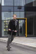 Casual male posing with electric scooter