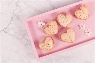 Sweet heart shaped French macaron sweets on pink tablet
