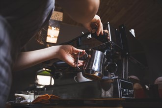 Female barista prepares espresso from coffee machine caf
