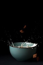 Cereals falling on a bowl with splashing milk