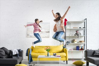 Mother daughter jumping couch