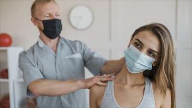 Male physiotherapist wearing medical mask during therapy session female patient