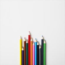 Row sharp colored pencils against white background