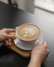 Female barista placing decorated cup coffee counter