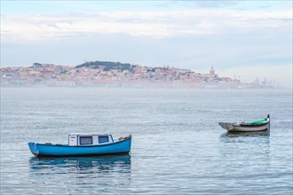 Fishing boats in Tagus river on misty morning with Lisbon in background with miSt Lisbon