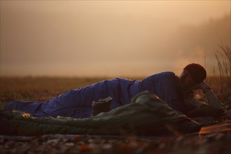 Man lying in a sleeping bag in frosty weather