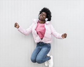 Portrait young woman with headphones jumping 1