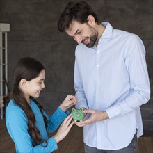 High angle father daughter with piggy bank