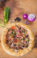 Top view of supreme pizza with olives and vegetables on wooden table. Delicious supreme pizza with vegetables on wooden background