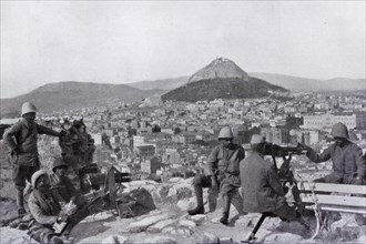 Greek soldiers stationed on the Acropolis with a canon and a machine gun in front of the Lycabettus mount