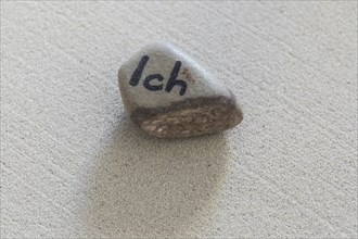 Stone with inscription I lying on sand