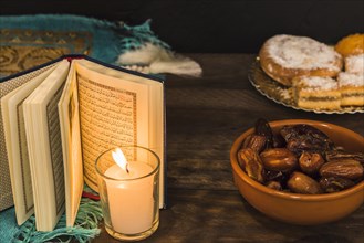 Dates pastry near burning candle opened book