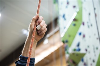 A person holding a rope for belaying in a climbing gym