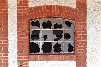 Old muntin window with broken glass of old abandoned building with red brick wall frame