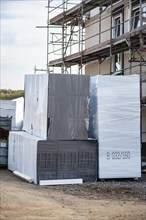 Stacked insulation boards in front of a house under construction