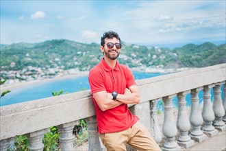 Handsome tourist man looking at the bay of San Juan del Sur. Portrait of smiling tourist in a viewpoint of a bay
