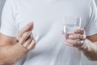 Close up man s hand holding white pill glass water hand
