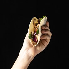 Close up hand holding taco with meat