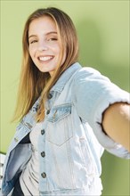 Smiling portrait blonde young woman against green backdrop