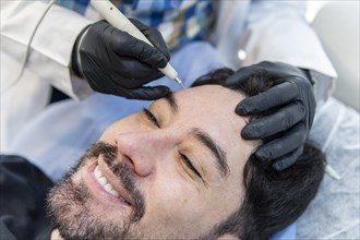 Latino man getting cosmetic treatment on his face