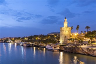 On the banks of the Guadalquivir River with the historic Torre del Oro tower at dusk
