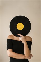 Young woman holding vinyl record her face