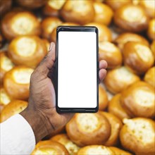 Crop hand with smartphone pastry background