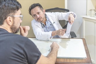 Latin doctor sitting at his desk explaining the treatment and prescription to his patient