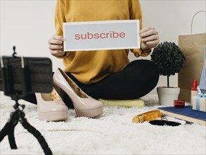 Female fashion blogger streaming home with smartphone subscribe word