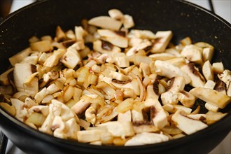 Closeup view of frying champignon mushrooms in a frying pan