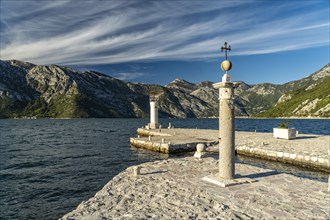 Cross and lighthouse on the artificial island of Gospa od Skrpjela near Perast on the Bay of Kotor