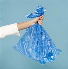 Woman holding blue plastic trash bag