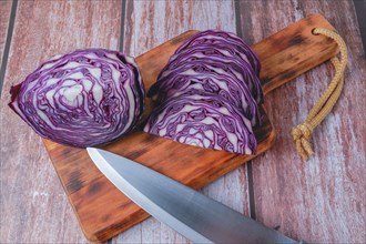 Sliced red cabbage on a wooden board with a knife in the foreground