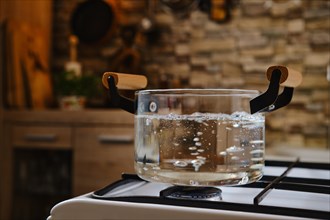 Water boiling in transparent glass pot on stove