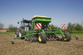 Tractor pulling John Deere 750A no-till seed drill working on farmland