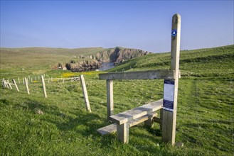 Wooden stile crossing on fence along the spectacular coastline with sea cliffs and stacks at Westerwick