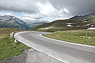 Photo with reduced dynamic range saturation HDR of view of winding road with tight curve road border small boundary posts mountain pass alpine mountain road alpine road pass road old Grossglockner Hig...