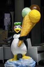 Large plastic penguin with plastic ice cream cone